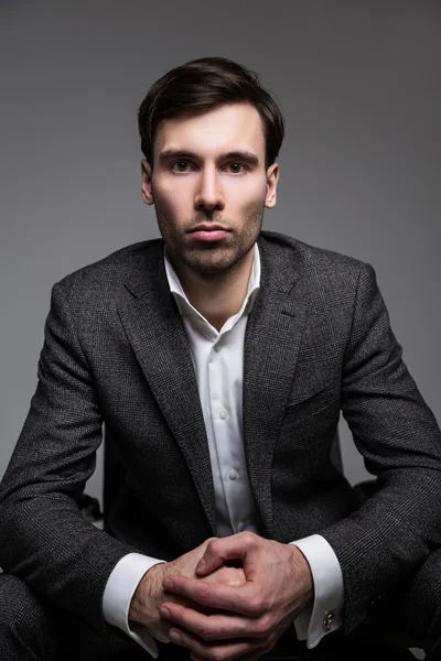 Businessman with fist in palm on dark background — Stock Photo, Image