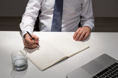 Ofis Masası oturma ve boş günlüğe yazma iş adamı. Yukarı alay