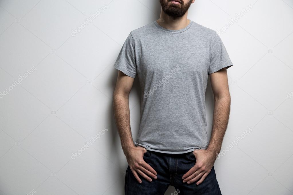 Young male body with blank grey t-shirt on light background. Mock up