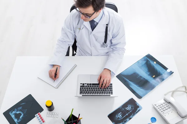 Doctor using laptop and reflecting — Stock Photo, Image