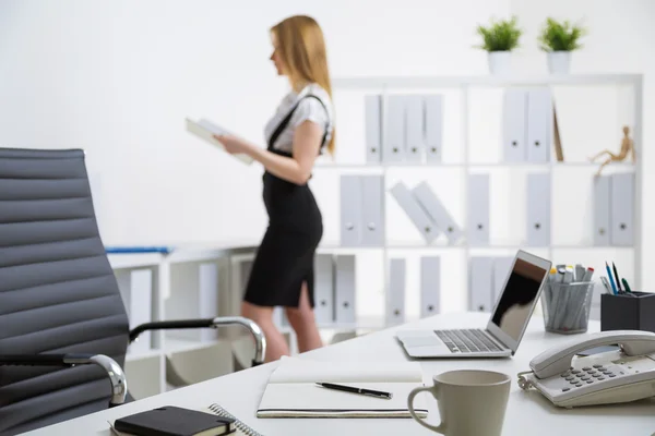 Office desk and standing businesswoman — Stock Photo, Image