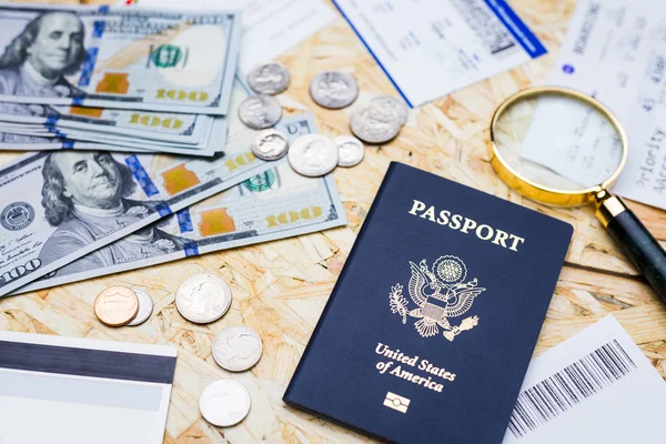 Vista superior da mesa de aparas de madeira com passaporte americano, moedas e notas de dólar, lupa e bilhetes. Conceito de viajar — Fotografia de Stock