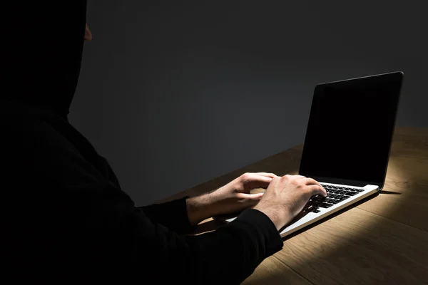 Man with hood hacking notebook — Stock Photo, Image