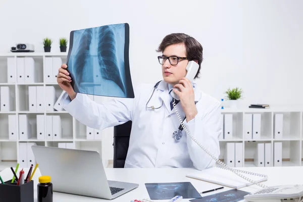 Doctor on phone holding x-ray — Stock Photo, Image
