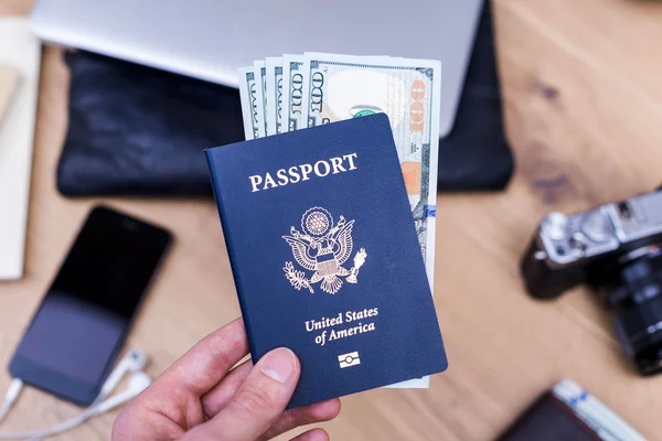 Mão segurando passaporte com dólares — Fotografia de Stock