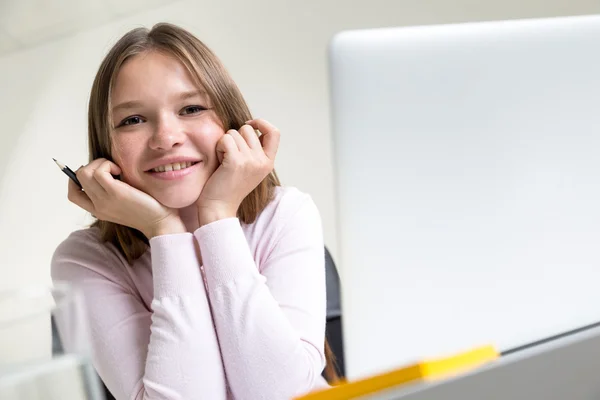 Ładna dziewczyna uśmiechający się o biurko — Zdjęcie stockowe