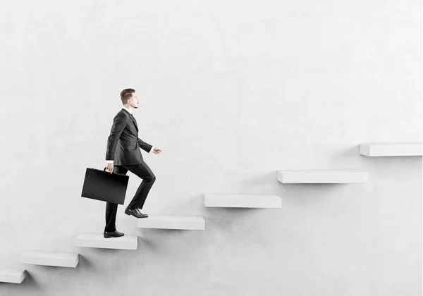 Conceito de sucesso com empresário escalando escada de concreto abstrata na parede — Fotografia de Stock