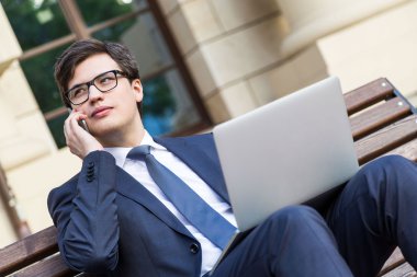 İşadamı ile telefon üstünde laptop