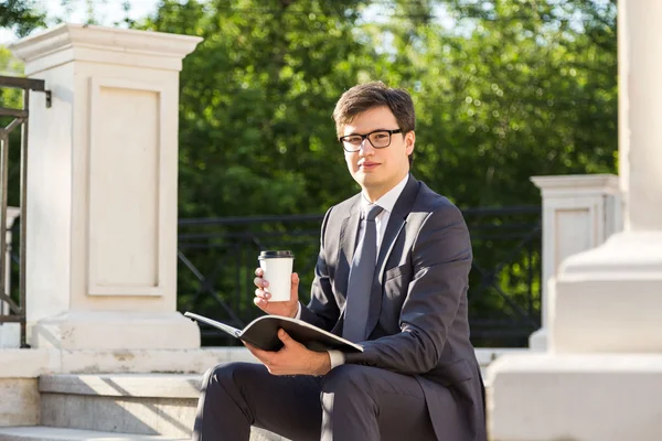 Бизнесмен с кофе и блокнотом — стоковое фото