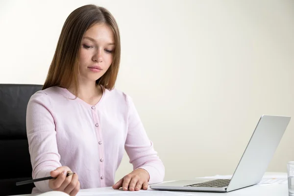 Woman doing paperwork using laptop — ストック写真