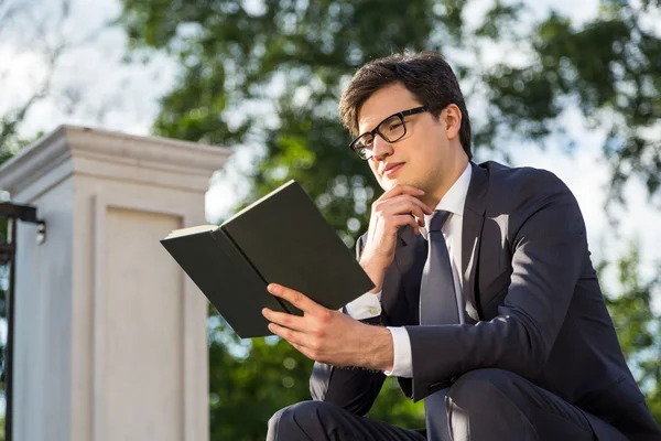 Вдумчивый бизнесмен читает книгу снаружи — стоковое фото
