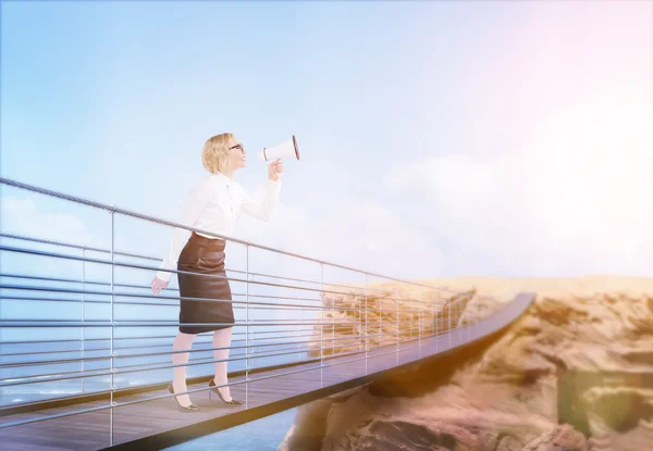 Woman on bridge using megaphone — Stockfoto