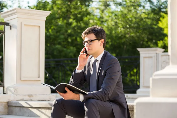 Hombre en el teléfono sujetando bloc de notas — Foto de Stock