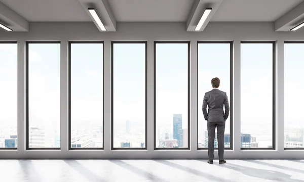 Zakenman in kantoorruimte met grote panoramische ramen — Stockfoto