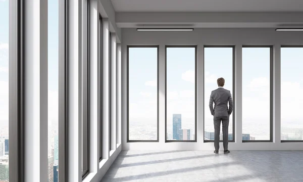 Бізнесмен дивиться в місті через панорамні вікна — стокове фото