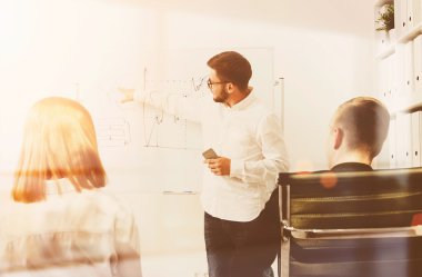 Beyaz tahtanın yanındaki işadamı grafikleri açıklıyor