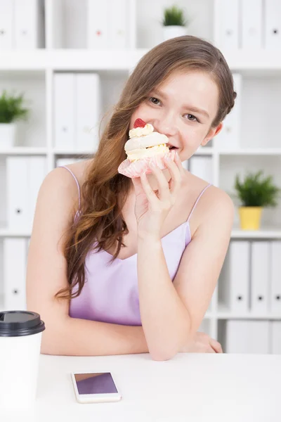 Chica comiendo cupcake y bebiendo café . — Foto de Stock