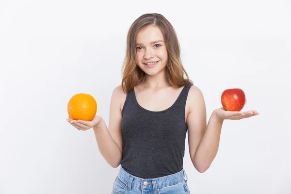 Lány farmerben gazdaság narancs és Alma — Stock Fotó