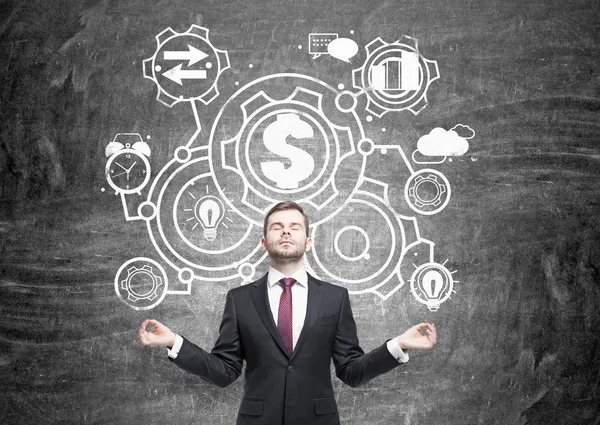 Businessman meditating in front of blackboard sketch — Stock Photo, Image