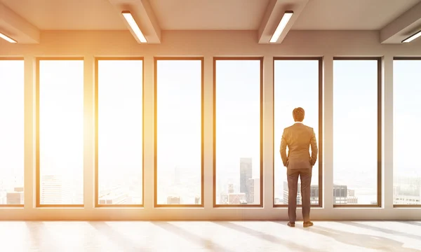 Homme d'affaires regardant par la fenêtre panoramique de la grande ville — Photo