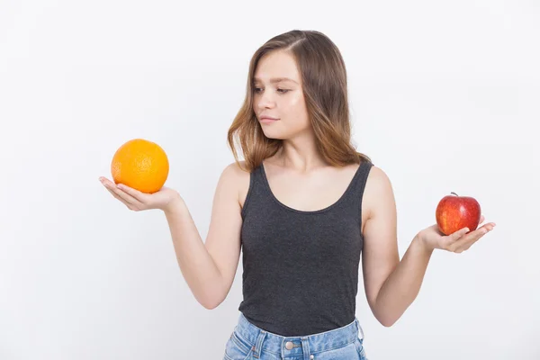 Chica en jeans y camiseta con manzana y naranja —  Fotos de Stock