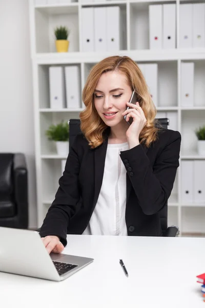 Mulher de negócios falando em seu telefone, sorrindo e olhando para a tela do laptop. Interior do escritório. Conceito de CEO — Fotografia de Stock