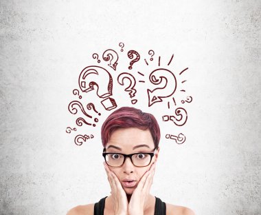 Beton duvara soru işareti çizimleri çizen bir kadın. Kafamda bir sürü soru var. 