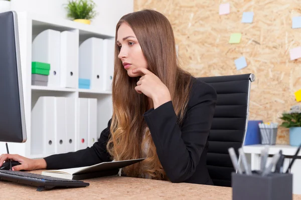 Mujer ligeramente aburrida en traje está examinando documento en la pantalla de la computadora. Concepto de buen asistente — Foto de Stock