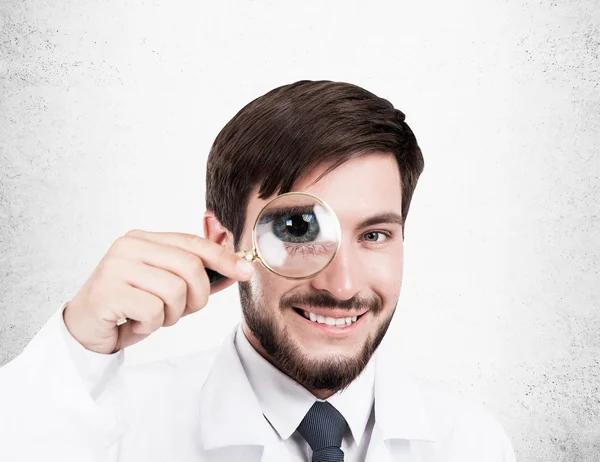 Doctor with magnifier and concrete wall — Stock Photo, Image