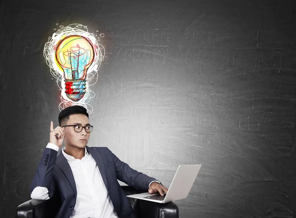 Hombre asiático con portátil y bombilla de colores — Foto de Stock