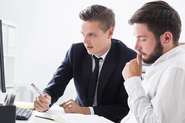 Dos socios comerciales que trabajan juntos en la mesa de la computadora mirando la pantalla y sus notas. Concepto de lluvia de ideas . — Foto de Stock