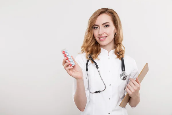 Woman doctor close up portrait with pills and clipboard — Stockfoto