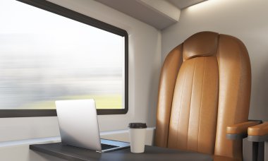 Tren bölmesinde kahverengi koltuk ve dizüstü bilgisayar
