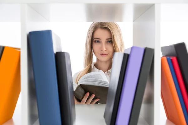 Blond meisje het lezen van een boek in de bibliotheek — Stockfoto