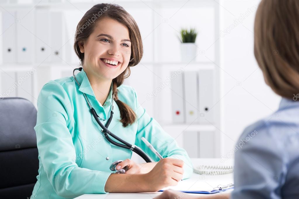 Young woman doctor is talking to her patient. She is really happy with treatment results and smiling broadly