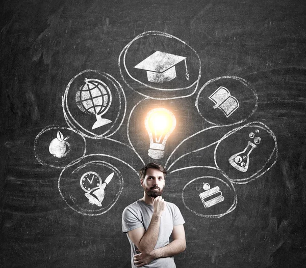 Man in T-shirt and blackboard with education sketches — Stock Photo, Image