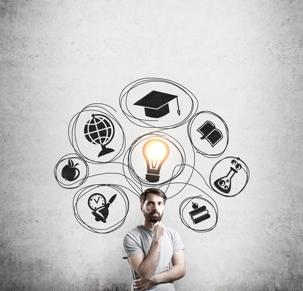 Man in T-shirt and concrete wall with education sketches — Stock Photo, Image