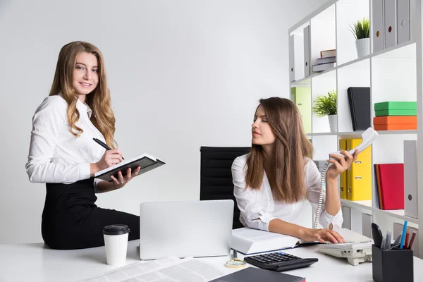 Två unga företag damer på arbetsplatsen i vit office — Stockfoto