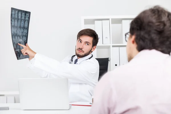 Bearded doctor is explaining to his patient how he is going to do his brain surgery and what can go wrong. Concept of medical talk — Stock Photo, Image