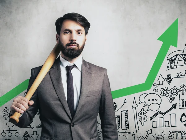 Retrato de hombre de negocios en traje sosteniendo bate de béisbol y de pie cerca de la pared de hormigón con flecha verde e imágenes de inicio. Imagen tonificada — Foto de Stock