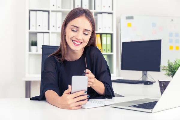 Leende kontorspersonal och hennes telefon — Stockfoto