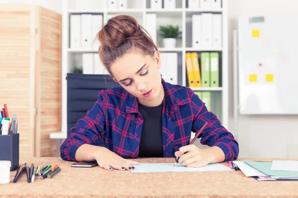 Ung kvinna arbetar på ritvit sitter på sitt kontor med whiteboard och pärmar på bokhyllor. Koncept för konstruktion — Stockfoto