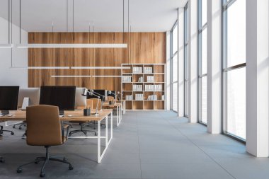 Açık uzay ofisi, bilgisayarlı ahşap masalar, üç boyutlu görüntüleme. Ahşap duvarın yanında klasörleri olan bir kitaplık. Çalışma alanı, insan yok.