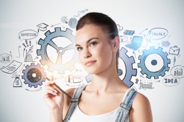 Üzerinde çarklar çizilmiş beton duvarın yanında duran kalemi olan güzel genç bir kadın. Takım çalışması ve beyin fırtınası kavramı