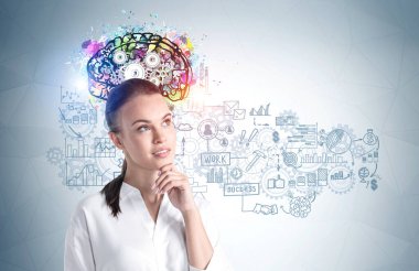 Üzerinde renkli beyin ve iş çizimi olan gri duvarın yanında duran düşünceli genç iş kadınının portresi..