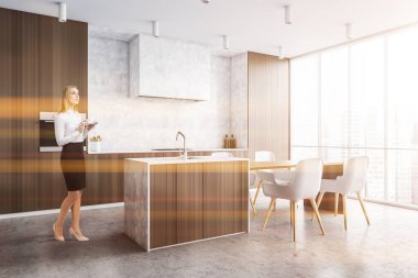 Modern mutfak köşesinde beyaz ve koyu ahşap duvarları, beton zemini ve barı olan güzel genç bir kadın. Tonu ayarlanmış resim