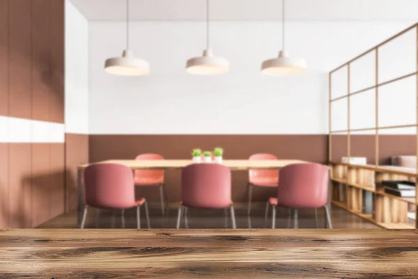 Wooden table for your product in blurry modern dining room with white and brown walls, wooden floor and long table with red chairs. 3d rendering