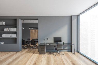 Gri ofis odası, sekreter ve geniş pencereli toplantı odası. Ofisin minimalist tarzı. Masada sandalye ve bilgisayar var. İnsan yok.
