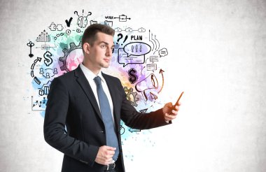 Genç Avrupalı işadamı beton duvarın yanında duran akıllı telefonuyla üzerine iş çizimi çizilmiş.