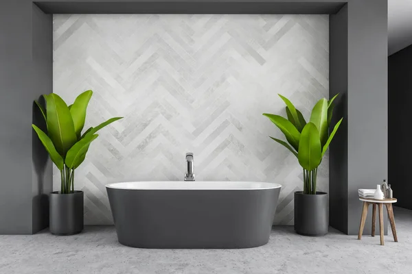 Grey bath against grey tile wall in a big bathroom with plants in pots on the sides. Stylish minimalist bathroom with soaps on the table, no people 3D rendering